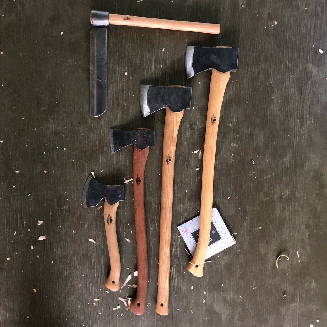 Green Woodworking Tools: 6 Essentials for the Workshop 5 Five wooden handled axes of different sizes resting on a dark wood surface.