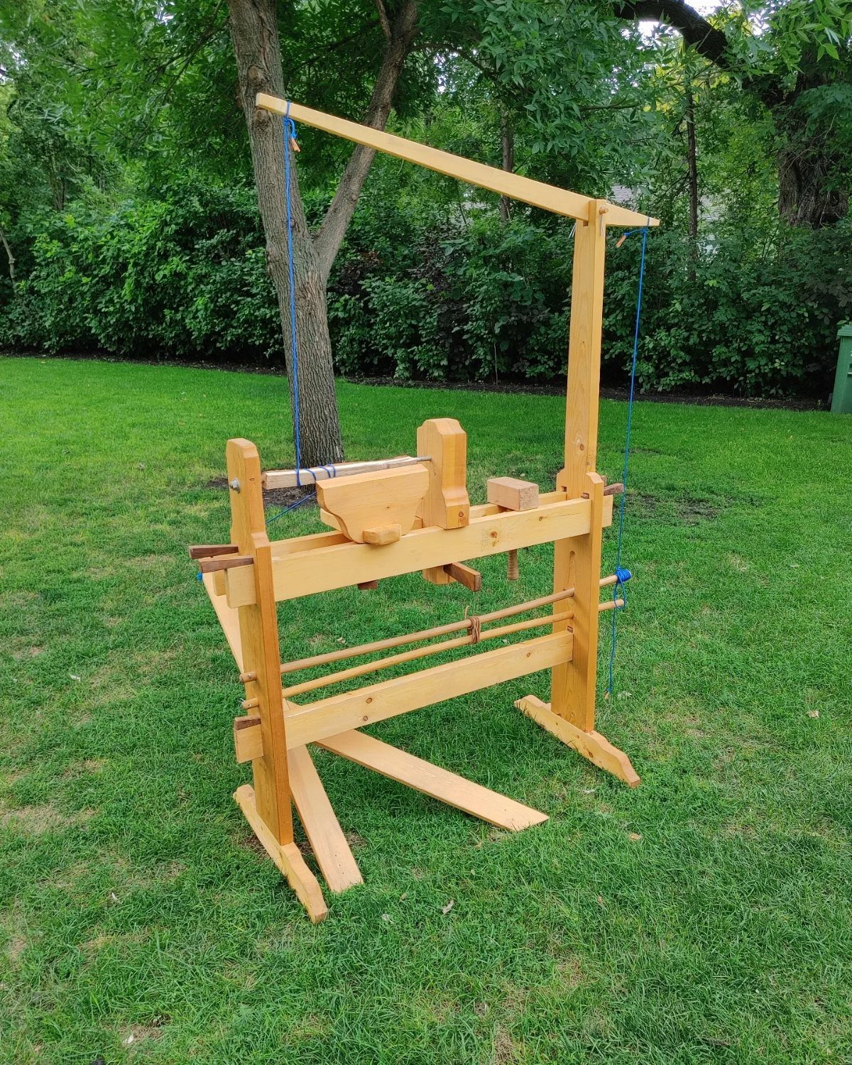 Green Woodworking Tools: 6 Essentials for the Workshop 4 Wooden pole lathe standing on a green lawn in a backyard setting.