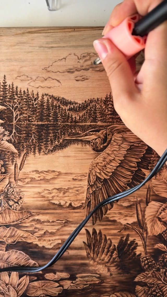 How to Burn Wood Art: 12 Ideas for Every Skill Level 11 Hand using a pyrography tool to burn a detailed heron landscape into wood.