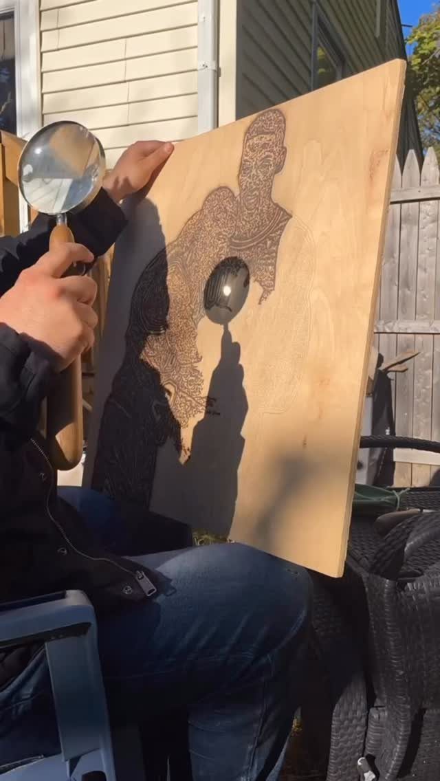 How to Burn Wood Art: 12 Ideas for Every Skill Level 9 Person using a magnifying glass to burn a portrait into a wooden board
