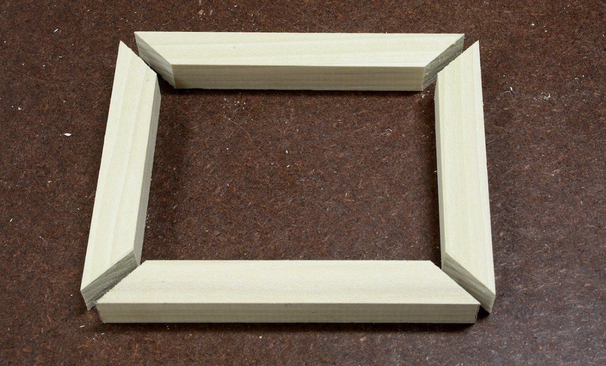 Four light wooden strips with mitered corners arranged in a rectangular frame.
