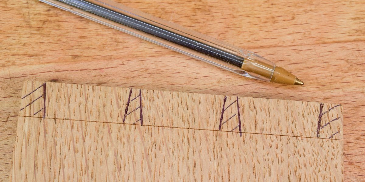 Wooden board with ink markings and a pen resting on a wooden surface.