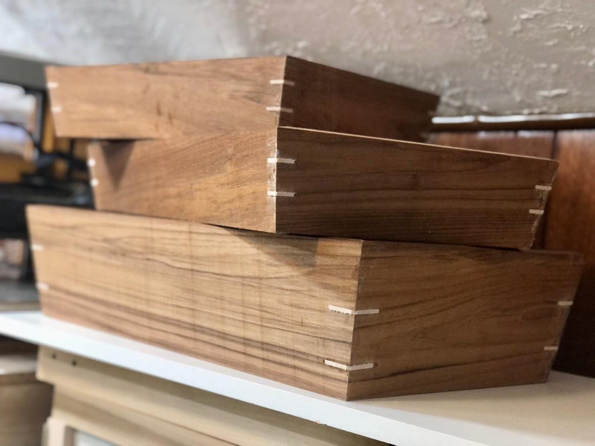 Three brown wooden boxes with light-colored splines reinforcing the mitered corner joints.