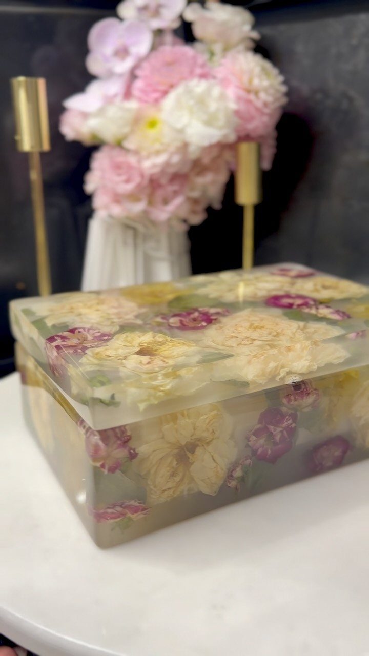 Resin jewelry box with embedded dried flowers on a white table with floral background