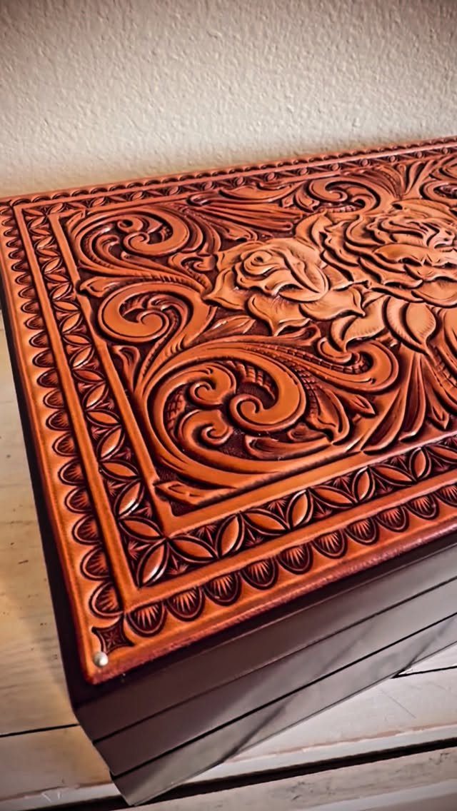 Handmade jewelry box with a brown tooled leather lid featuring carved rose patterns.