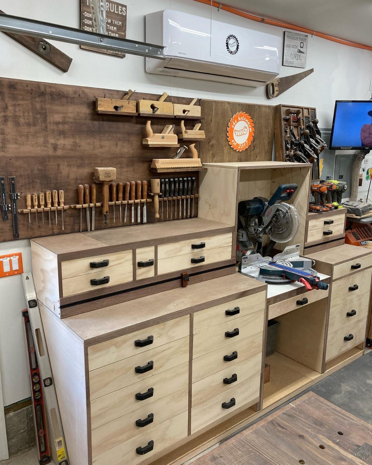 Miter saw recessed into a custom plywood workbench with multiple storage drawers.
