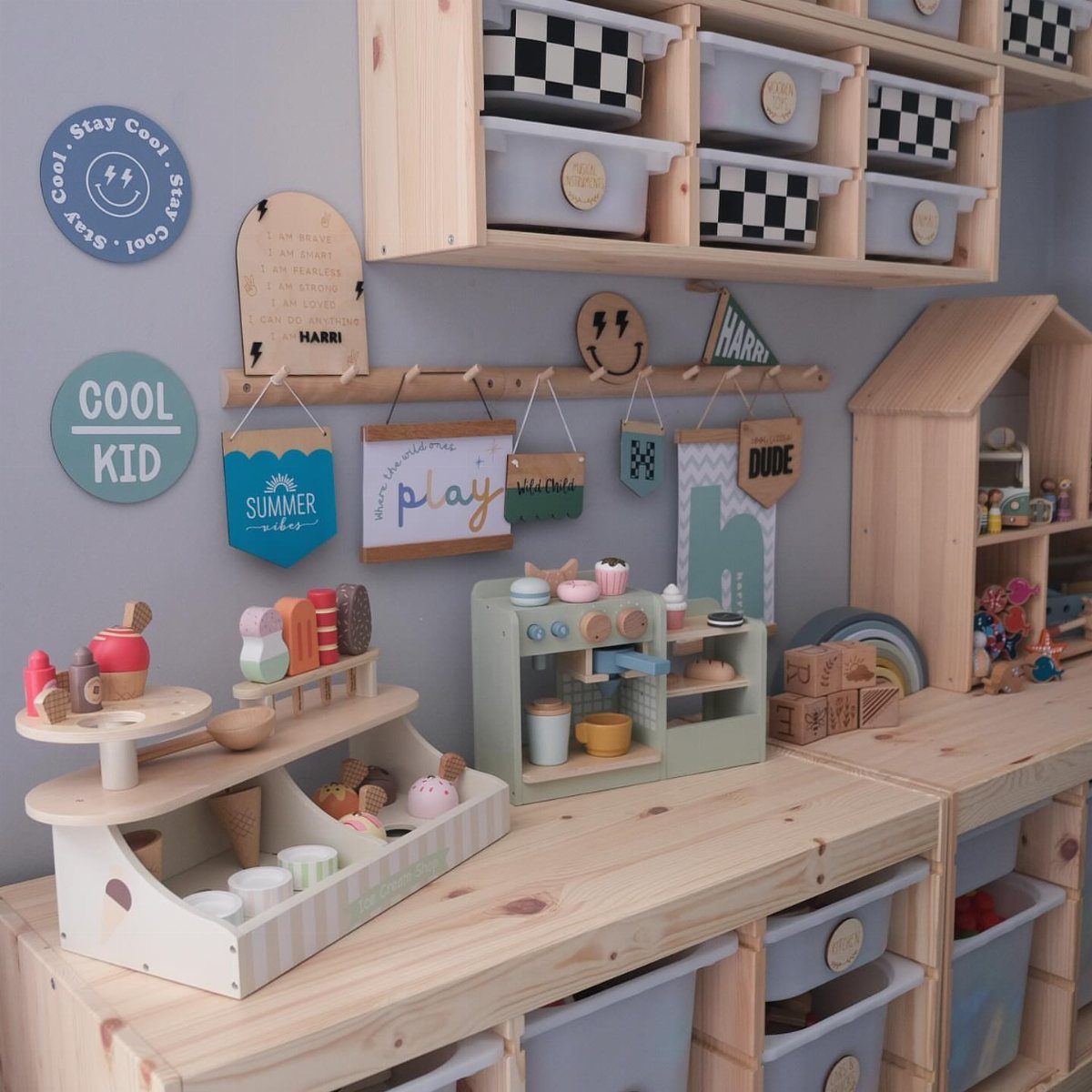 Wooden peg rail on a grey wall holding colorful children's signs and decorations.