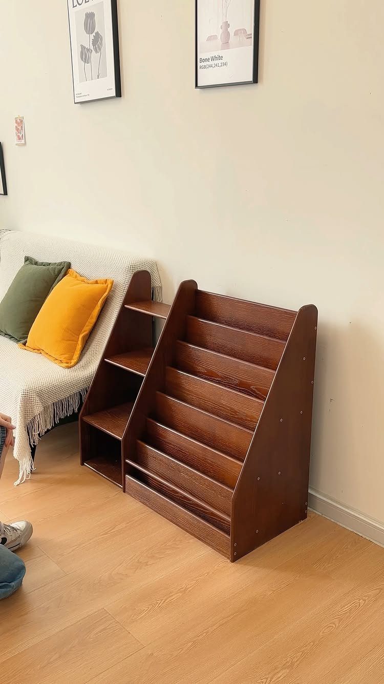 Brown wooden magazine rack with slanted slots sitting on a light wood floor.
