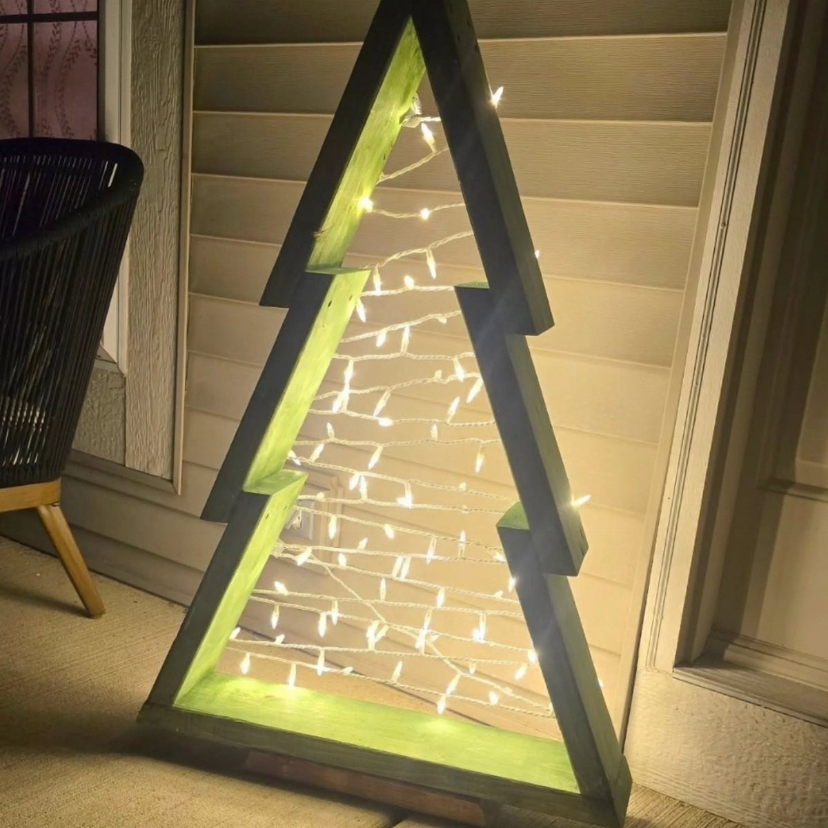 Wooden Christmas tree frame with lime green interior and glowing white fairy lights.