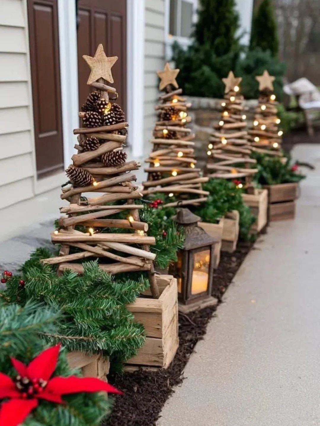Wooden branch Christmas trees with stars and lights lining a house walkway.