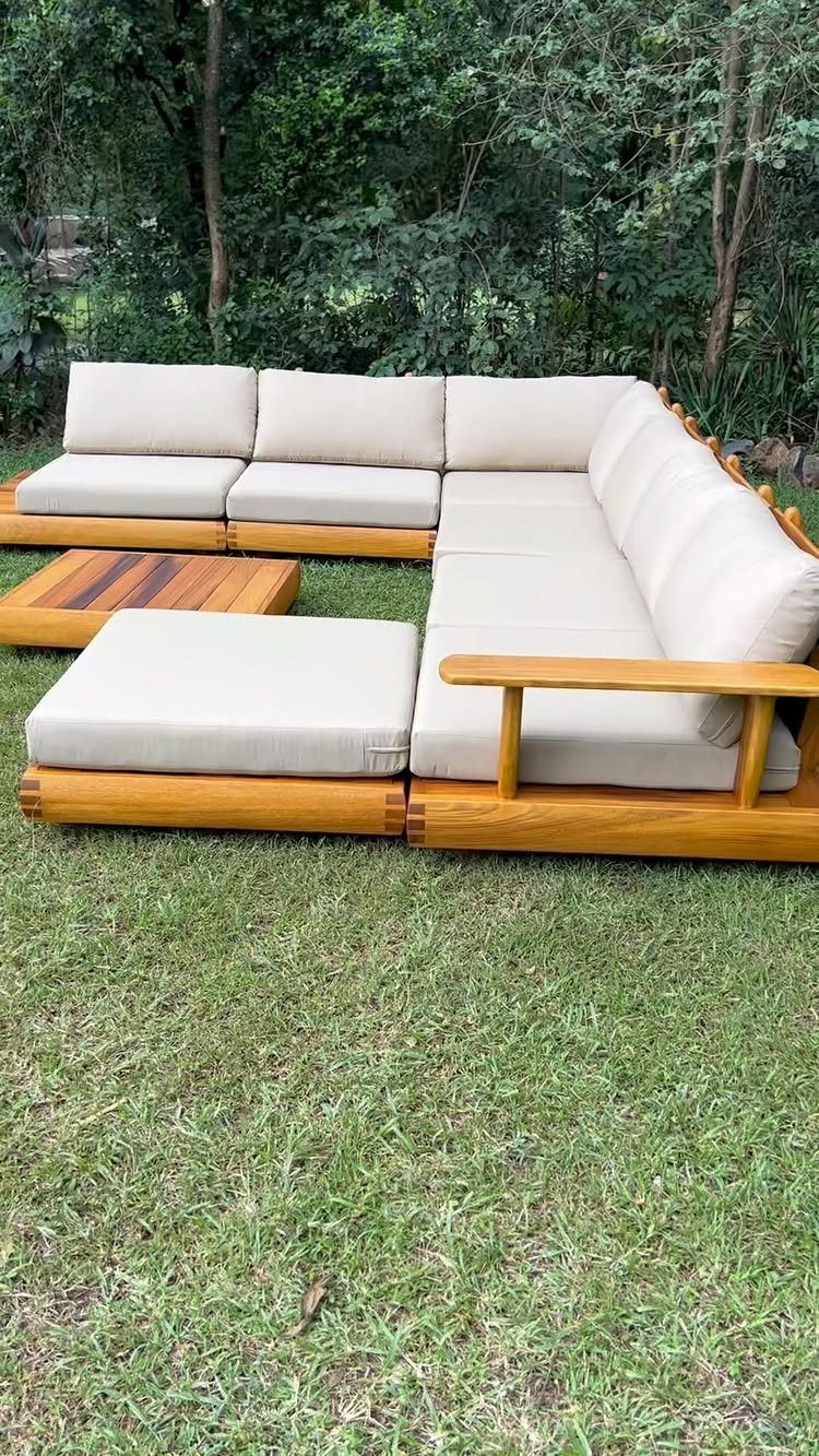L-shaped outdoor wooden couch with cream cushions on a green lawn