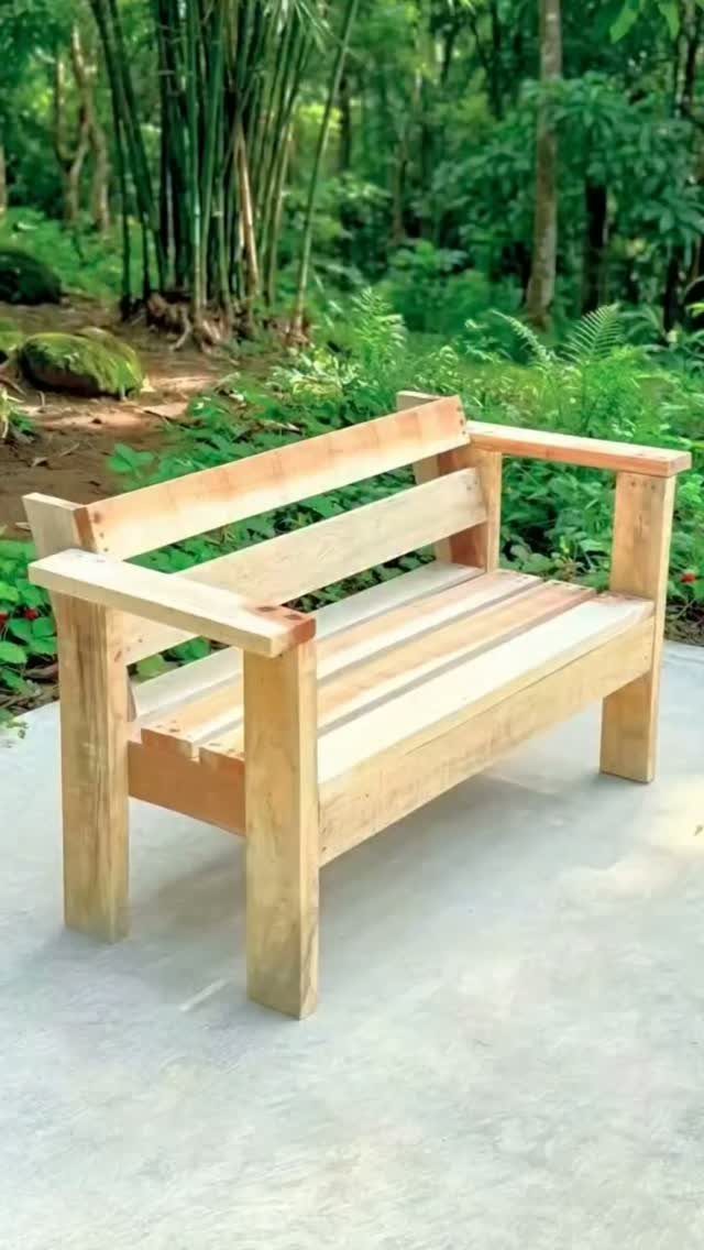 Light wooden outdoor couch with slatted design set against a green forest background.