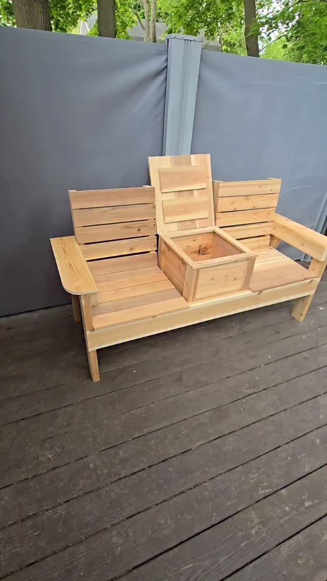 Wooden outdoor couch with a built-in cooler box on a dark grey deck.
