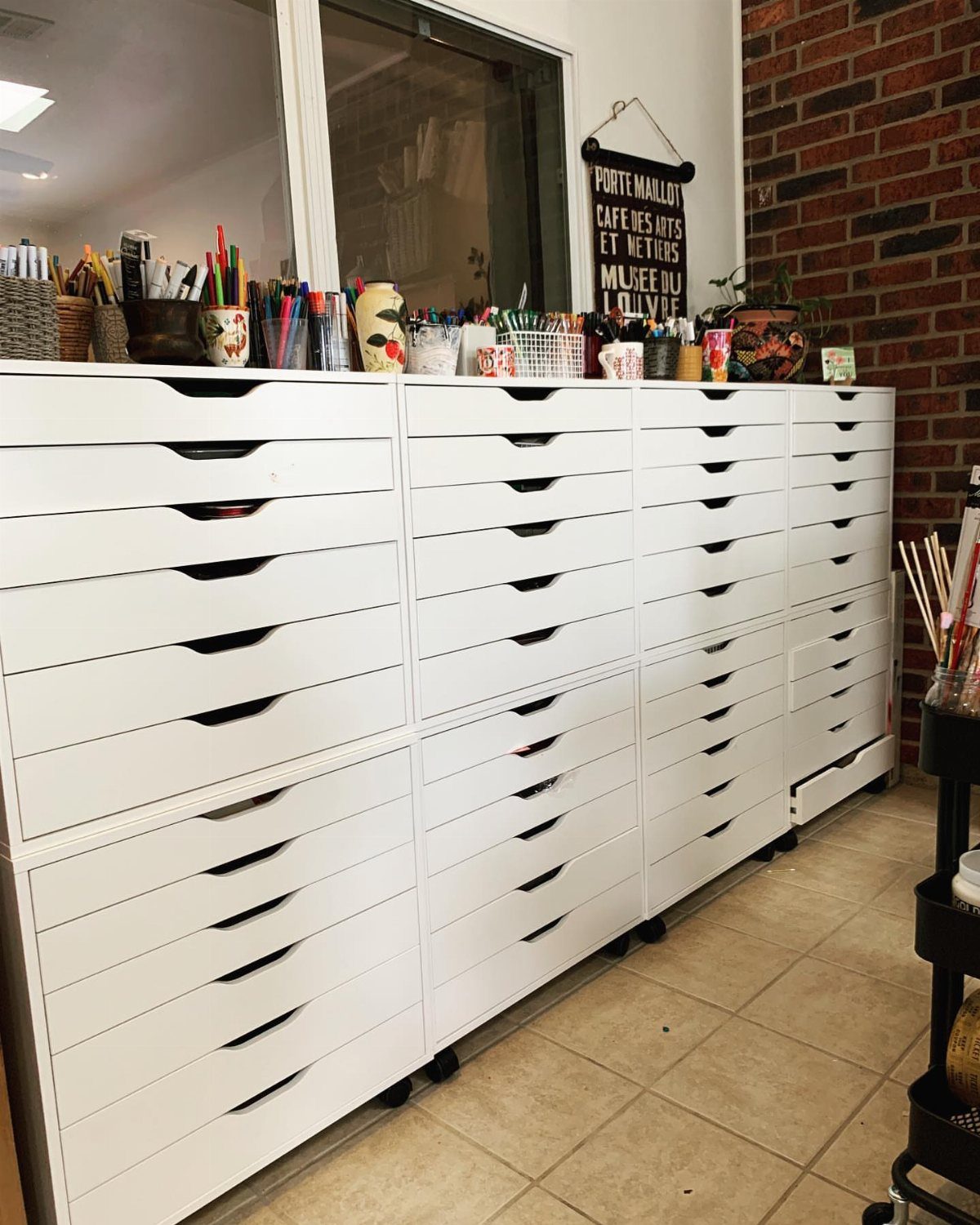 Paint Storage Cabinet Ideas: 6 Options for Art and Workshop 2 White multi-drawer storage cabinet filled with art supplies and paintbrushes in a studio.