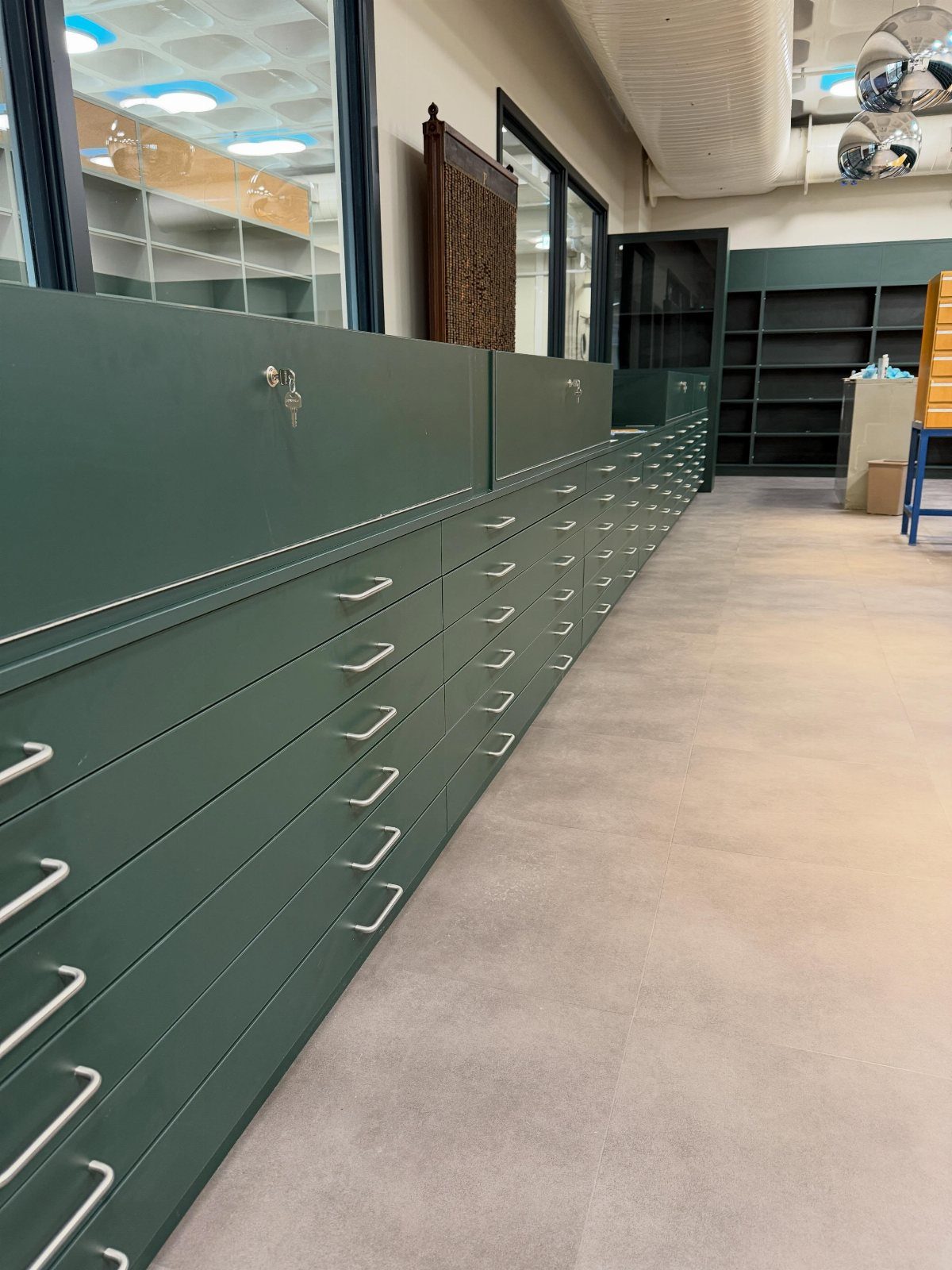 Paint Storage Cabinet Ideas: 6 Options for Art and Workshop 4 Dark green storage cabinet with many shallow drawers in a bright studio space.