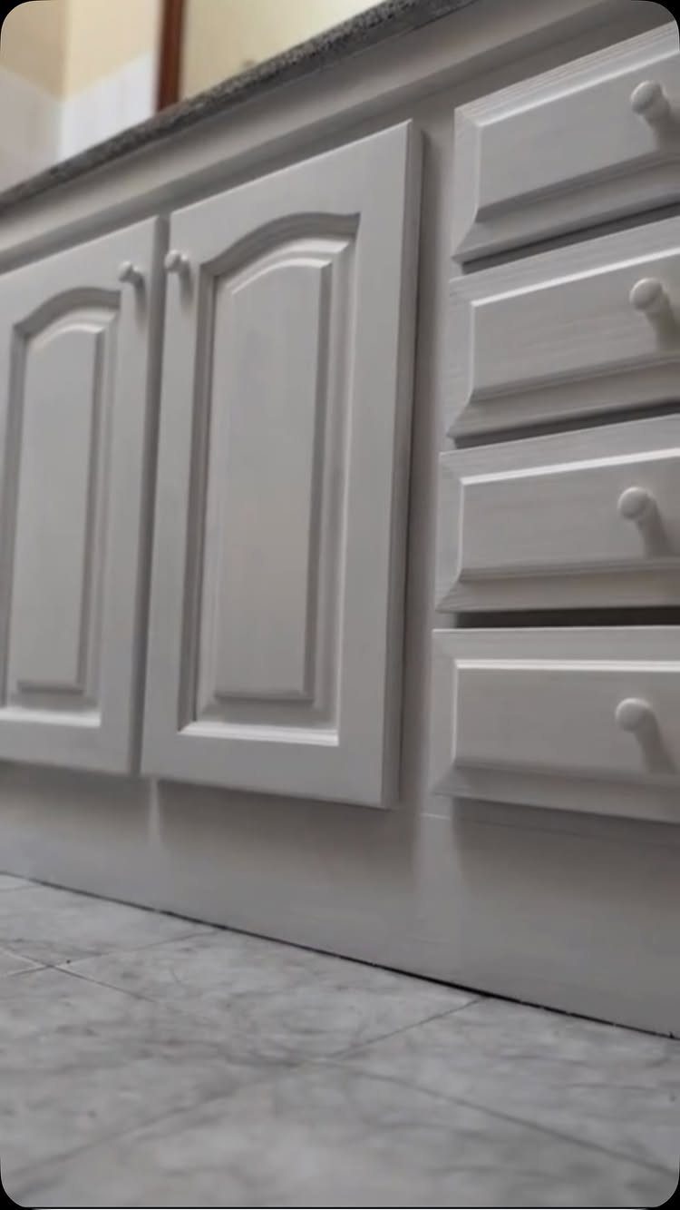 White painted kitchen cabinets and drawers with a matte finish and round knobs.