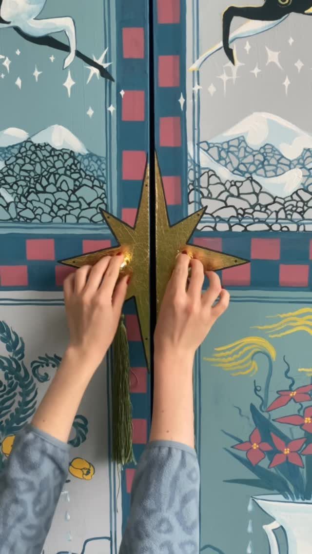 Painted armoire with a gold star handle and detailed landscape illustrations on the doors.