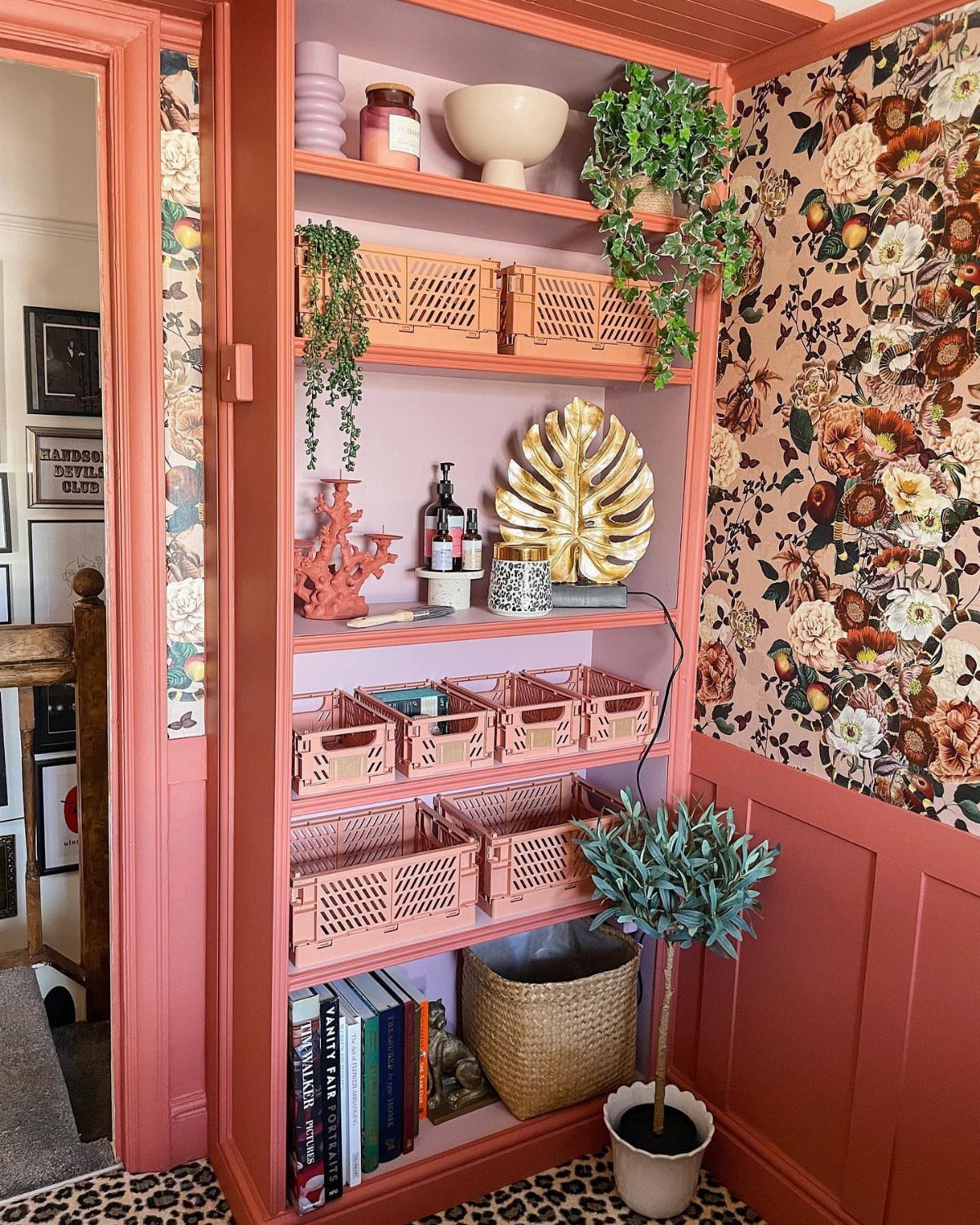 Coral-pink built-in shelves matching the wall color, decorated with plants and pink baskets.