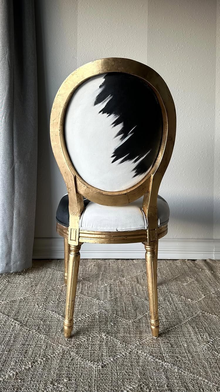 Gold oval-back chair with black and white abstract painted fabric upholstery.