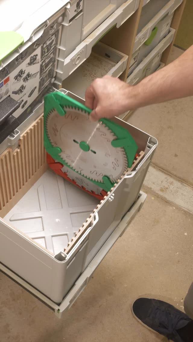 Circular saw blade in a green plastic holder inside a white storage bin.
