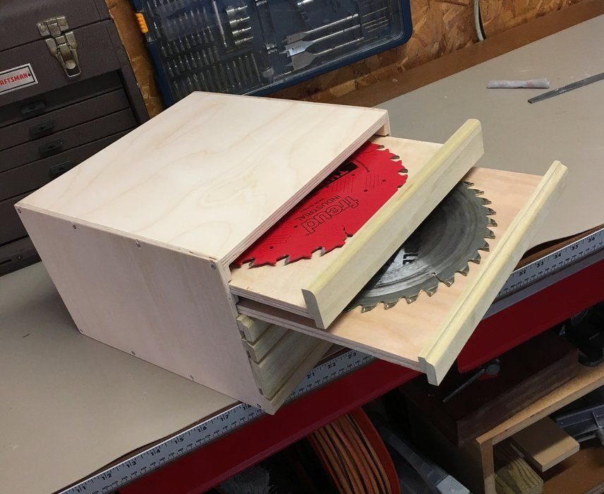Wooden table saw blade organizer with pull-out trays holding circular saw blades.