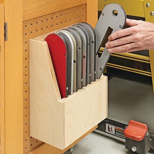 Wooden table saw blade rack mounted on a pegboard holding various saw blades