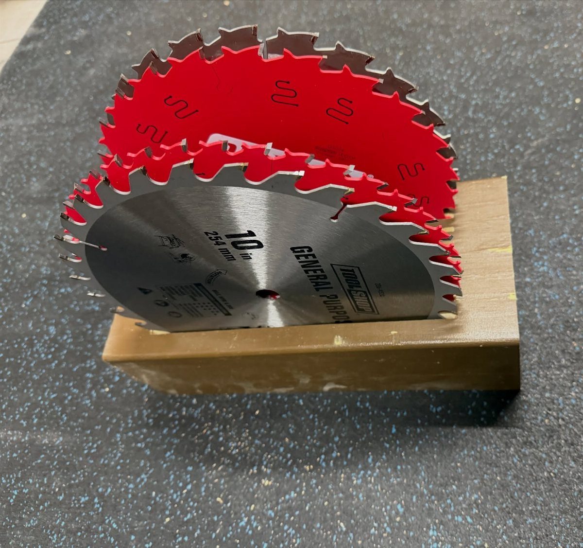 Circular saw blades stored upright in a simple wooden block holder.