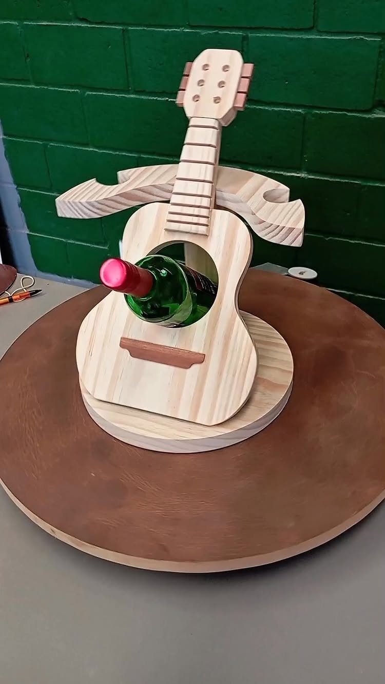 Guitar-shaped wooden wine holder holding a green bottle on a circular base.