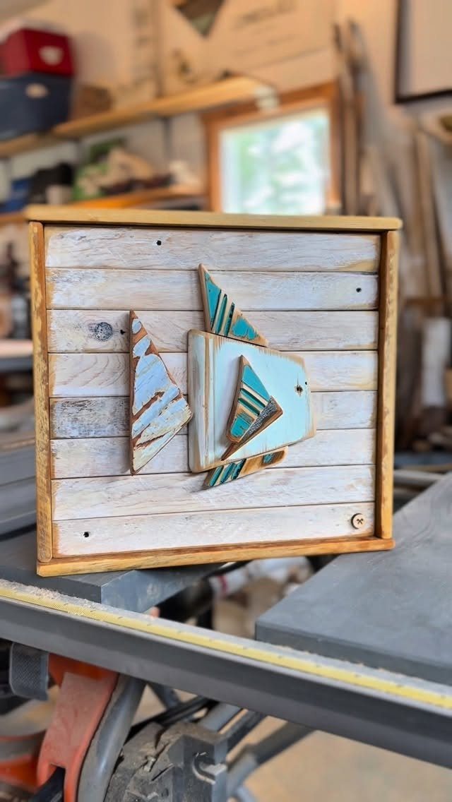 Geometric fish art made from painted scrap wood on a light plank background.