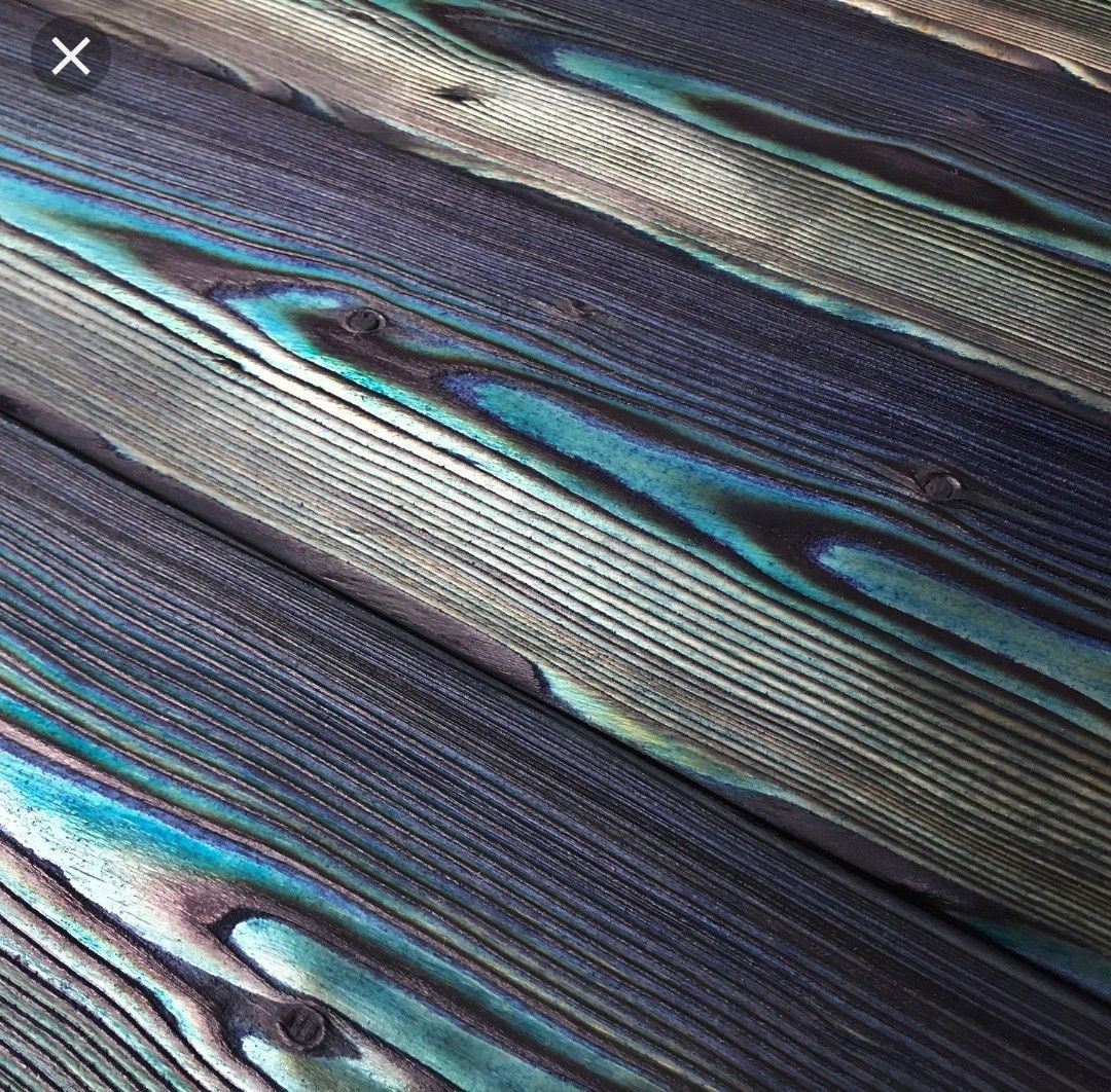 Charred wooden planks with deep black finish and vibrant turquoise color stain highlights.