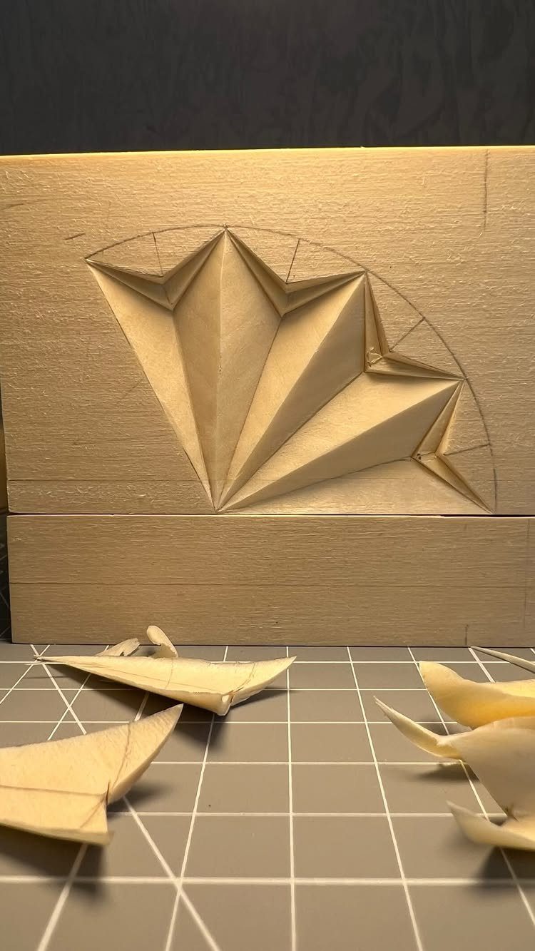 Geometric star pattern carved into a light wood block with shavings on a mat.