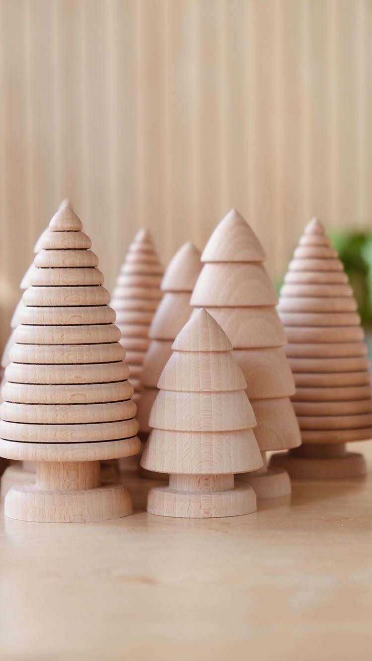 Small wooden carved pine trees with tiered layers on a light wood surface.