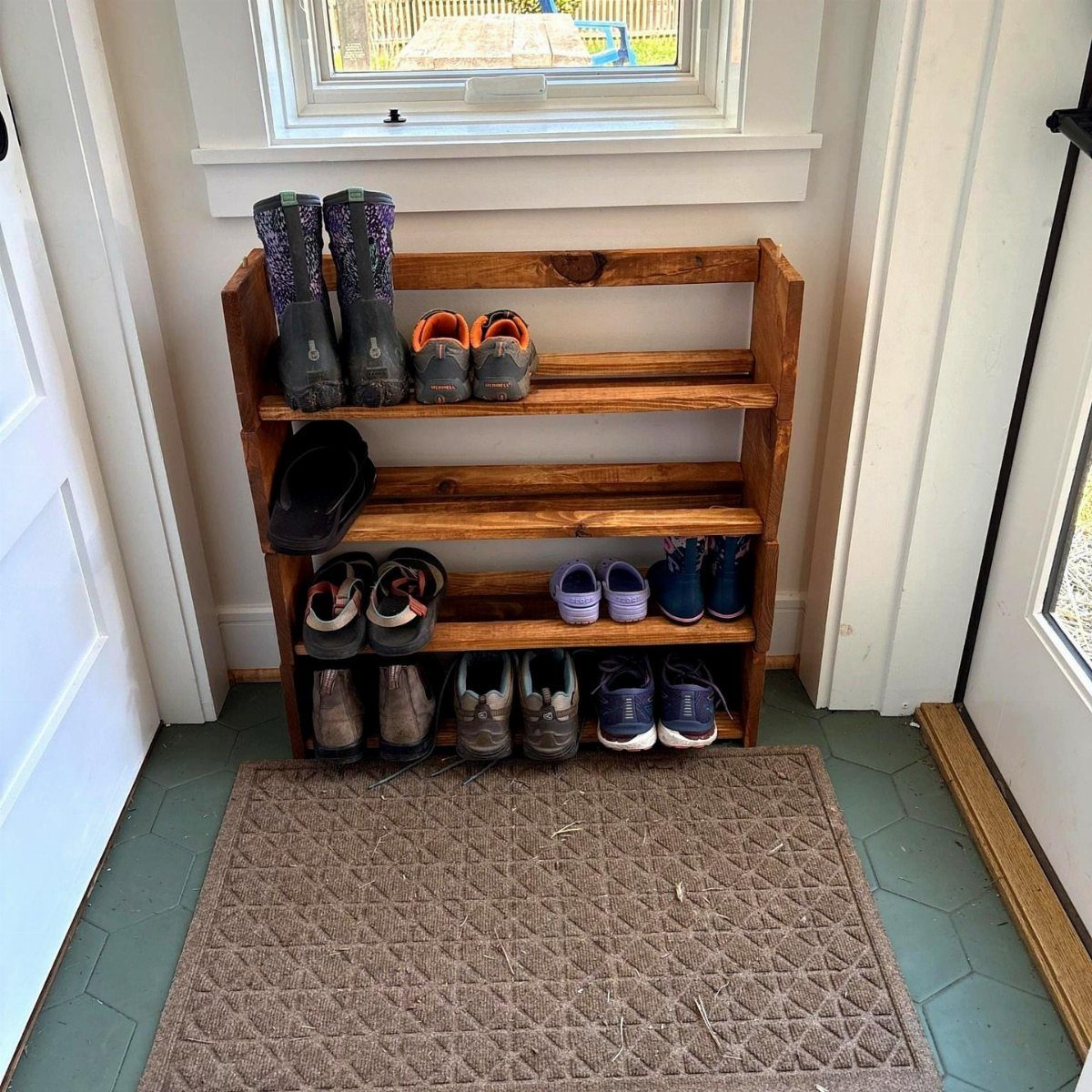 12 Small Wood Projects for Beginners to Build This Weekend 8 Wooden four-tier boot rack holding various shoes and boots in an entryway.