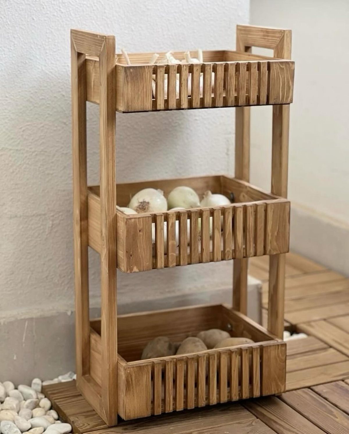 12 Small Wood Projects for Beginners to Build This Weekend 11 Three-tiered wooden vegetable storage bin holding onions and potatoes against a white wall.