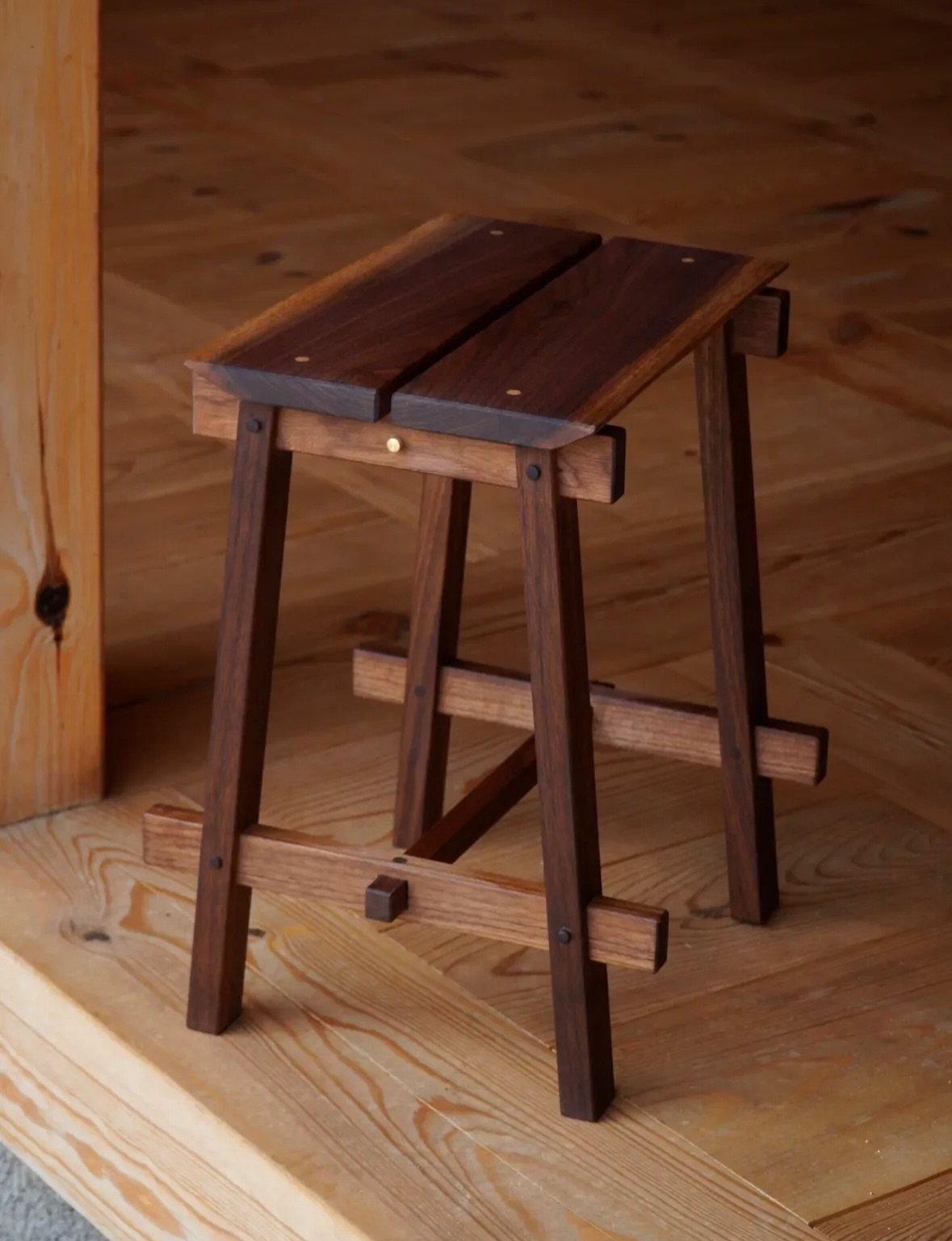 12 Small Wood Projects for Beginners to Build This Weekend 5 Handcrafted wooden stool with dark brown finish and light wood supports on wooden floor.