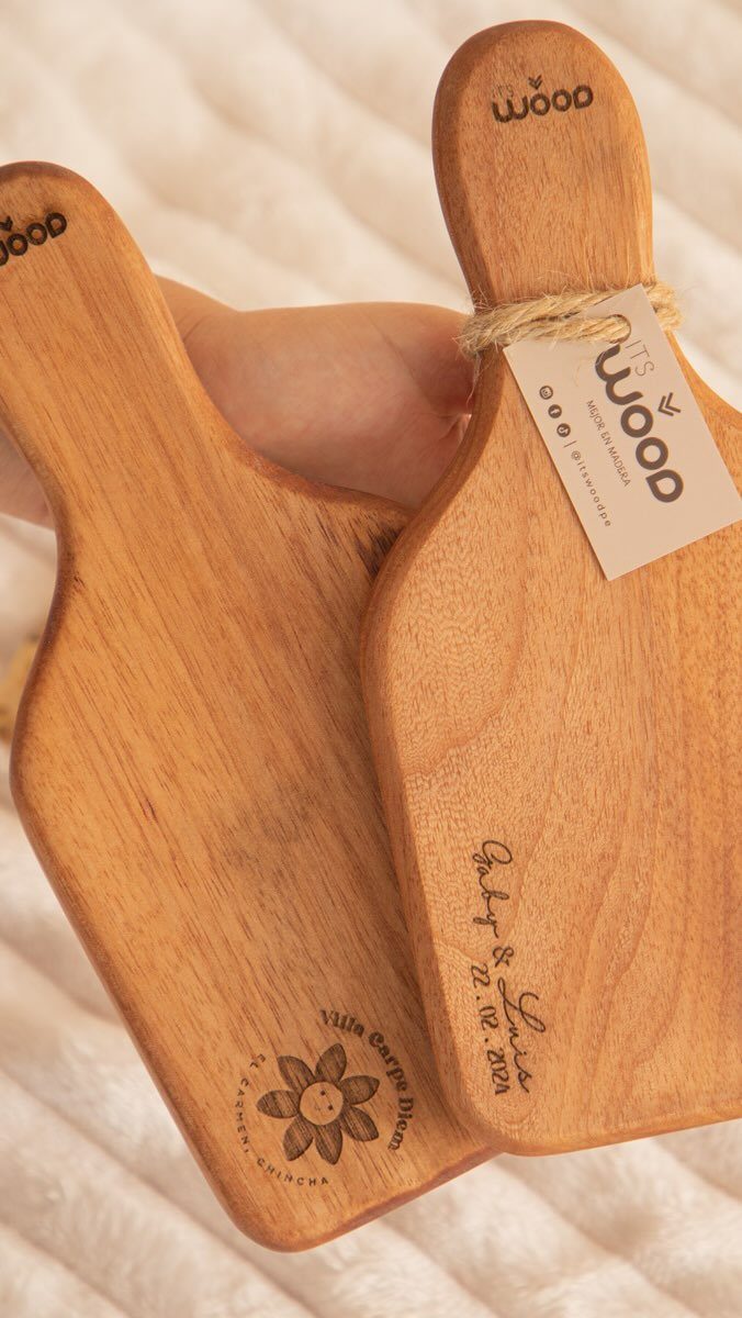Two small engraved wooden cutting boards resting on a white textured fabric background.