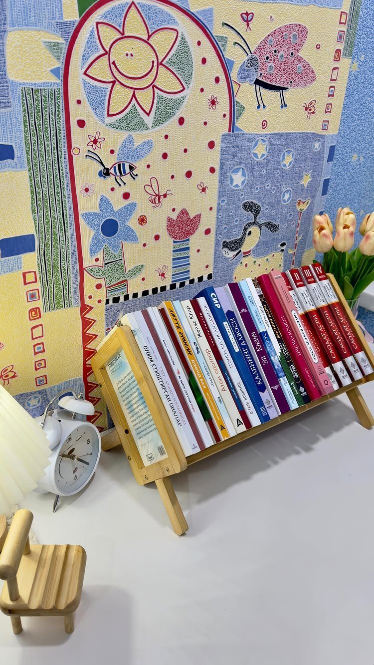 Wooden book holder holding colorful books against a bright illustrated background.
