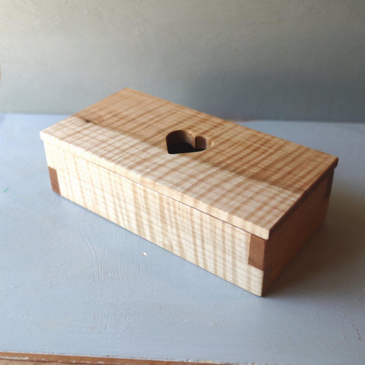 Small wooden jewelry box with a heart-shaped cutout on the lid.