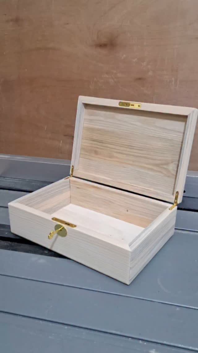 Small open unfinished pine wood jewelry box with gold hinges and latch.