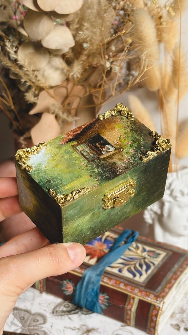 Small green weathered wooden jewelry box with gold accents held in a hand