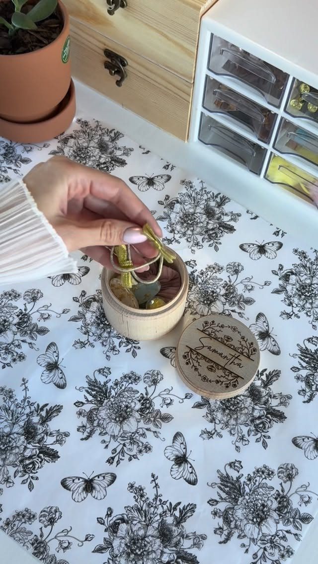 Small round wooden jewelry box with engraved lid on floral butterfly fabric