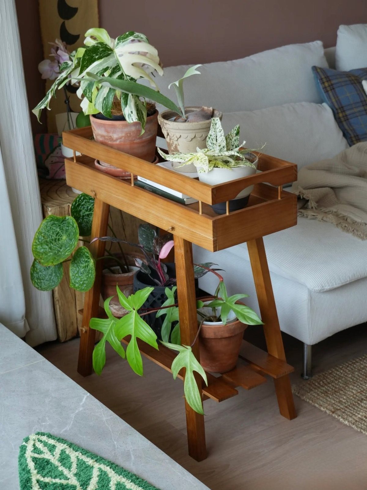 Small Wooden Rack Ideas: 9 Shelves, Stands and Holders 4 Two-tier brown wooden plant stand with potted greenery next to a white sofa.