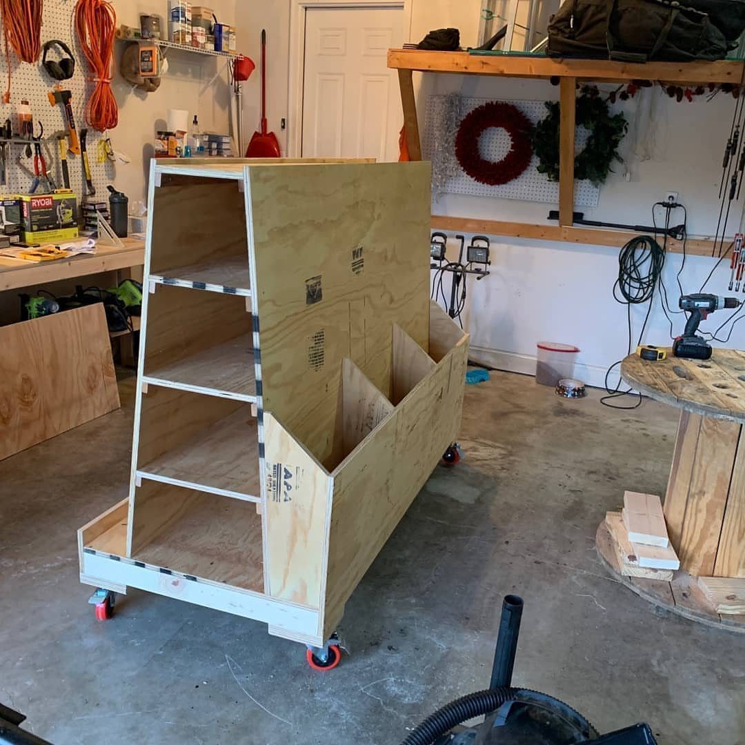 Plywood rolling lumber cart with multiple storage slots in a home woodshop garage.