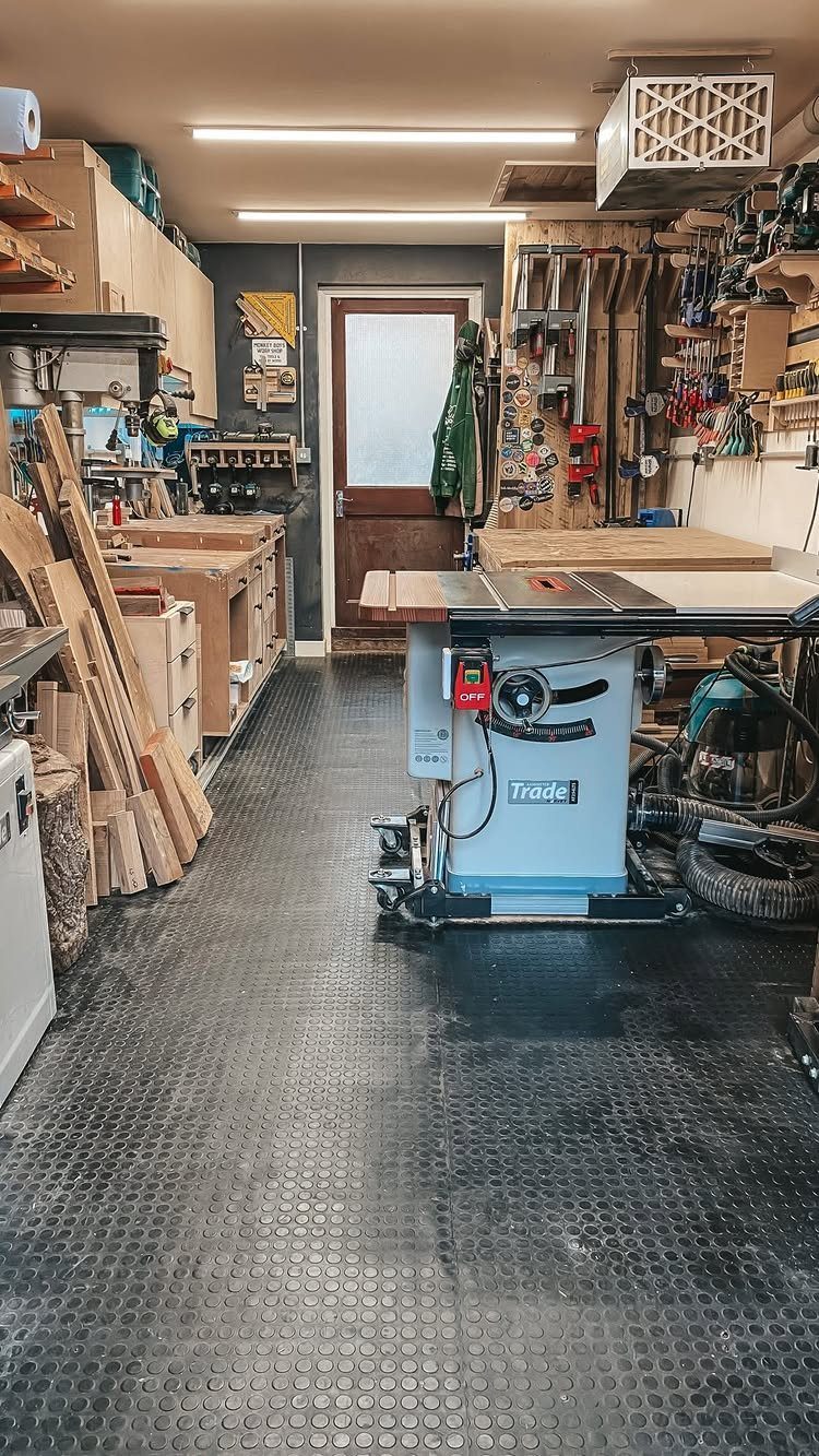 Small woodworking shop with a table saw, tool wall, and lumber storage.