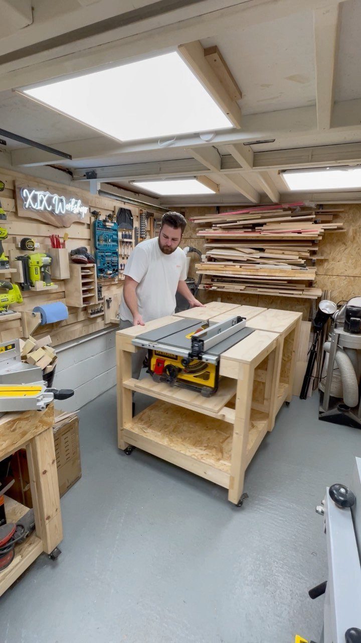 Wooden rolling workbench with integrated table saw in a well-organized small workshop.