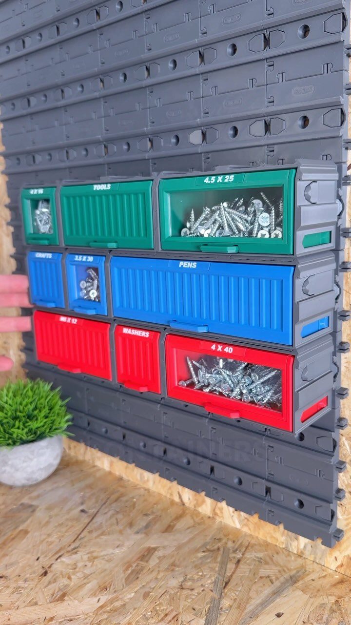 Colorful plastic hardware bins mounted on a grey modular workshop wall storage system.