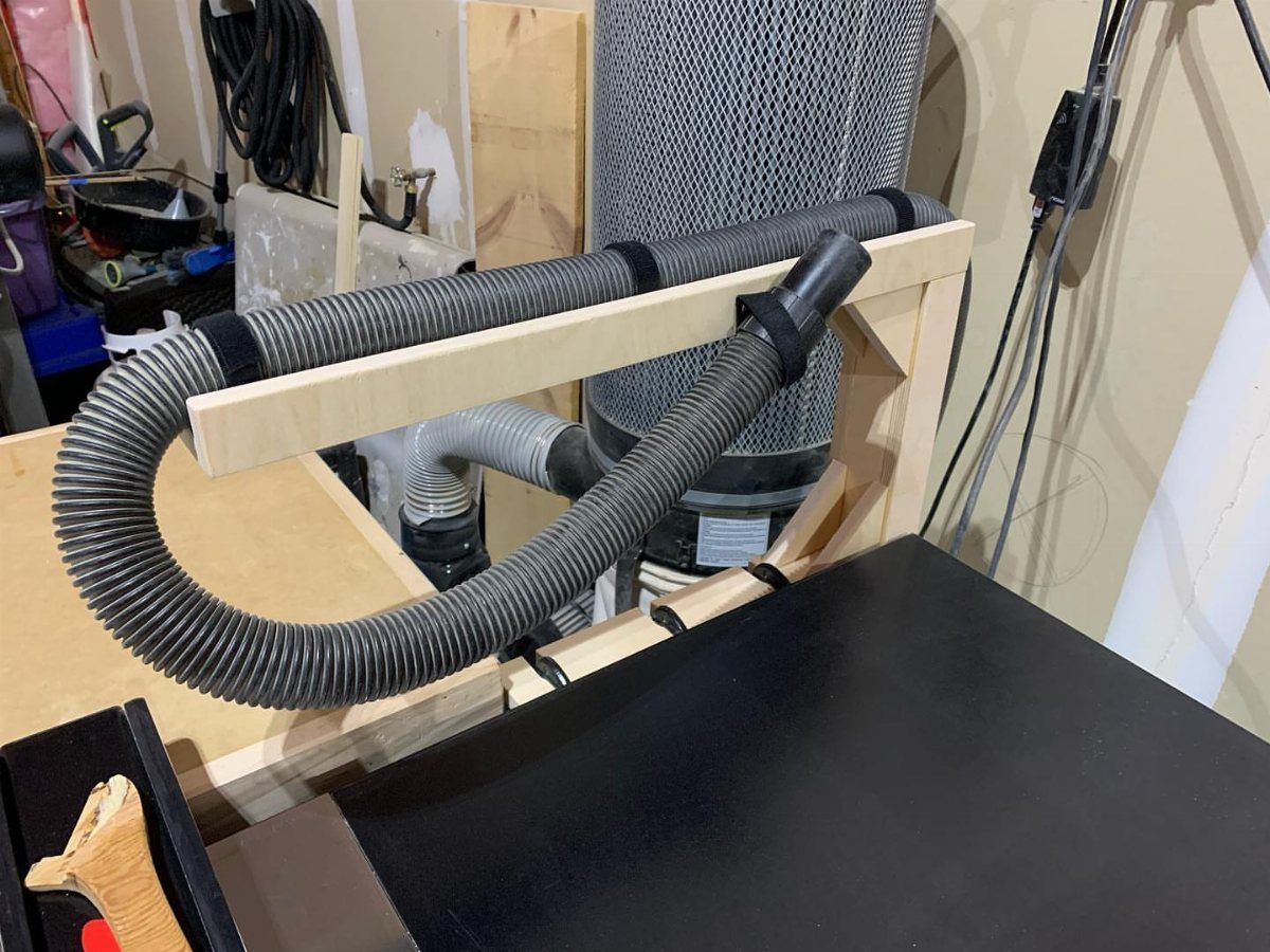 Table Saw Dust Collection: 5 Ideas for a Cleaner Shop 2 Flexible vacuum hose mounted on a wooden overarm dust collection system above a saw.