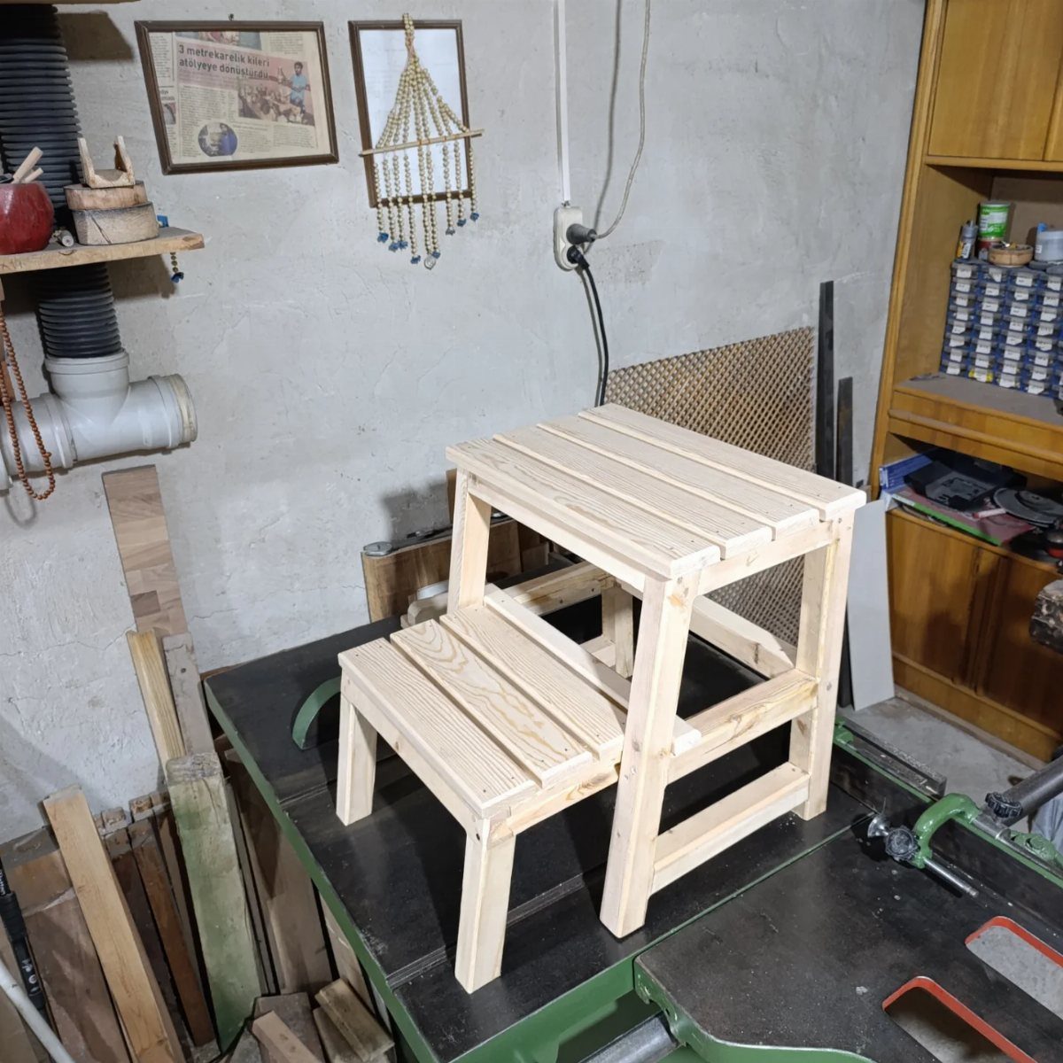 Table Saw Projects: 15 Ideas to Build This Weekend 9 Wooden two-step stool resting on a green table saw in a workshop.
