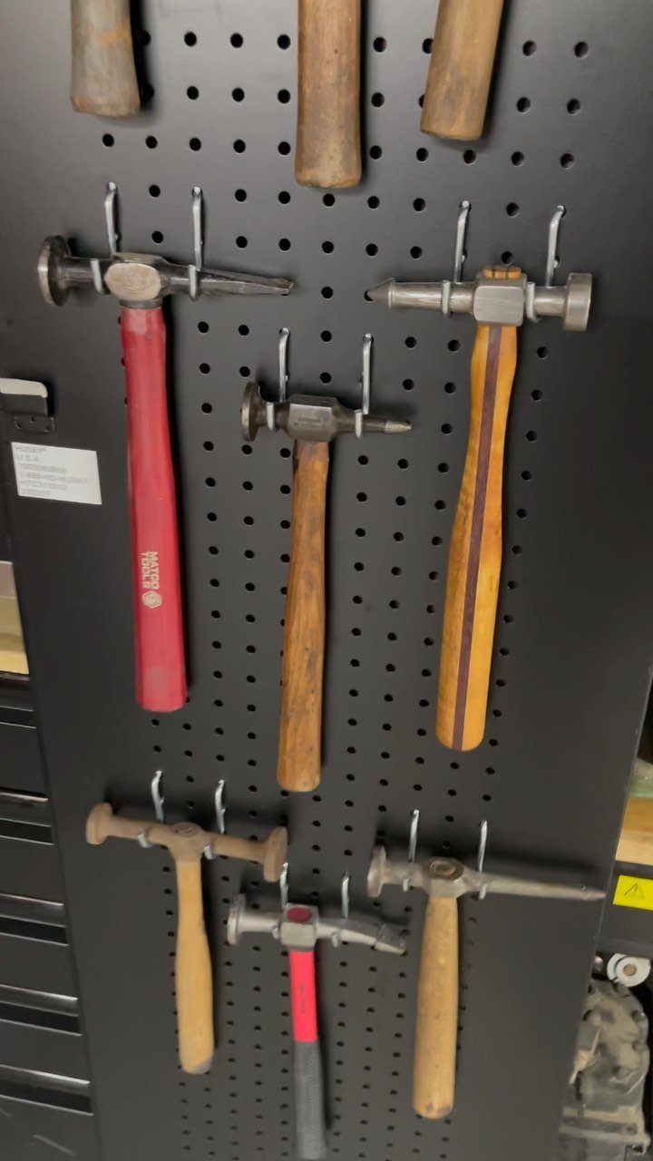 9 Tool Organization Wall Ideas for Garage and Shop 7 Hammers of various sizes organized on a black pegboard wall with metal hooks.