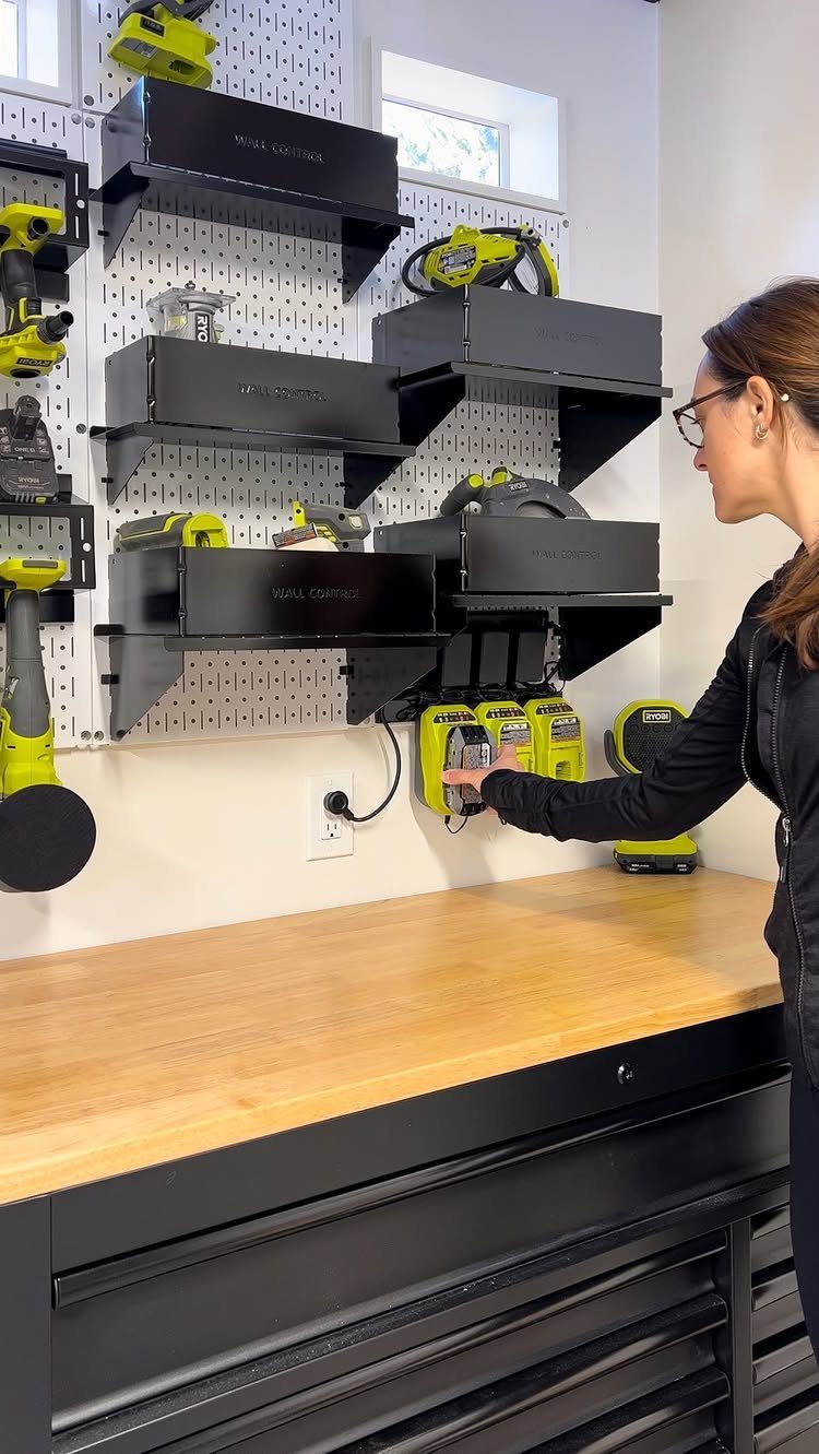 9 Tool Organization Wall Ideas for Garage and Shop 6 Woman organizing yellow power tools on a white pegboard wall above a workbench.